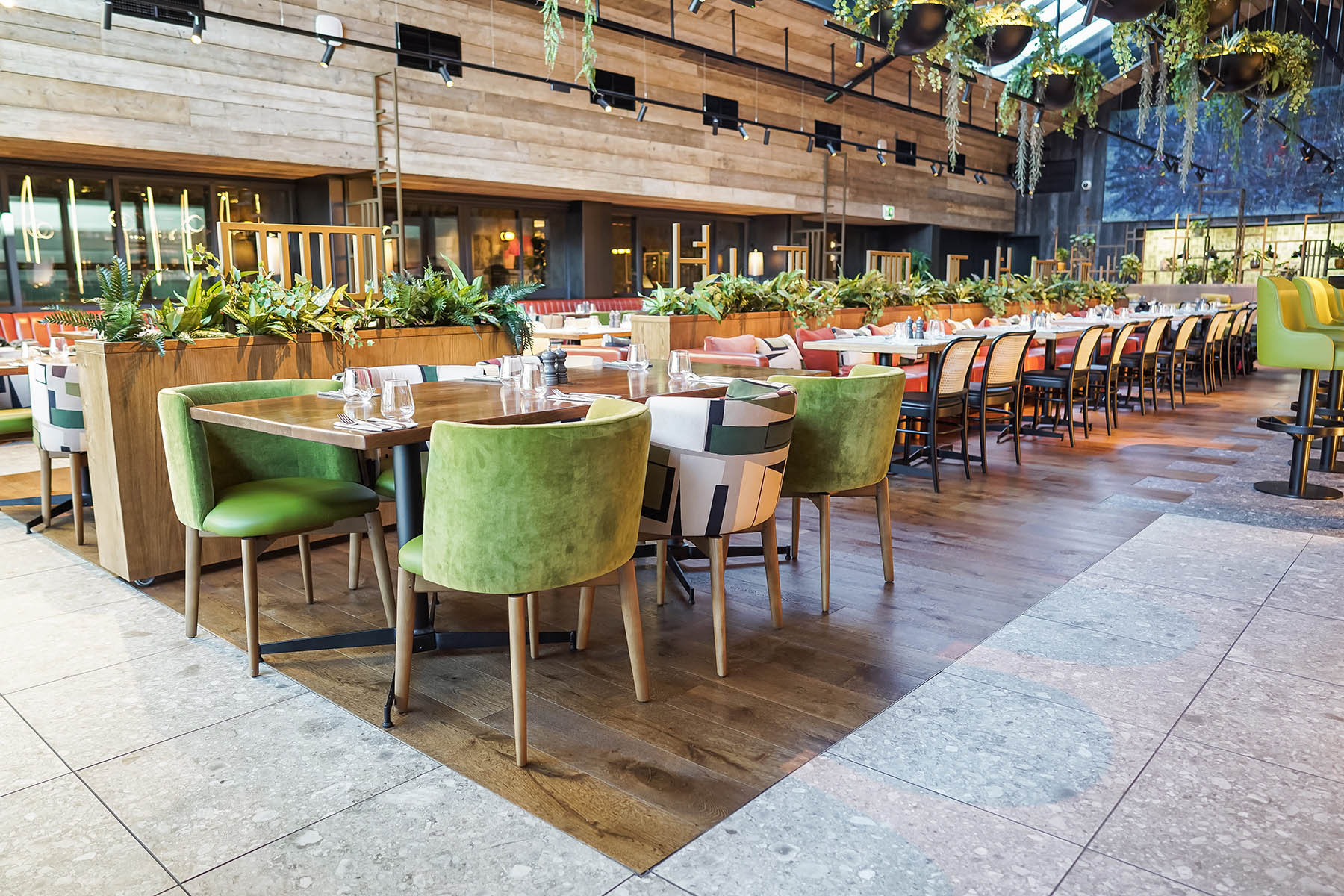 Seating area with natural wood tones, lush greenery, and bold patterned upholstery at Burleigh Court Hotel’s Fifty The Street.