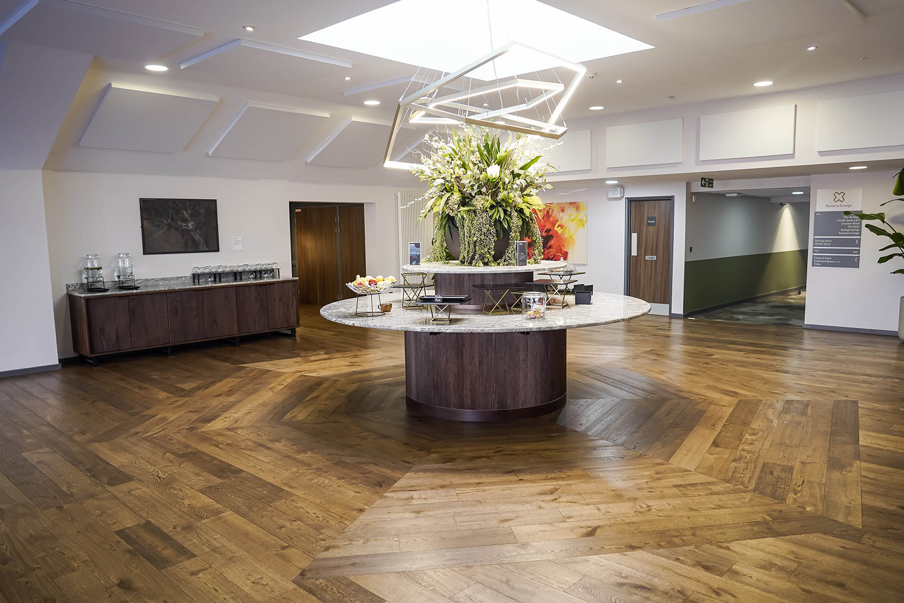 Chevron-patterned wood flooring forming a heptagonal design surrounded by horizontal planks in the island buffet area.