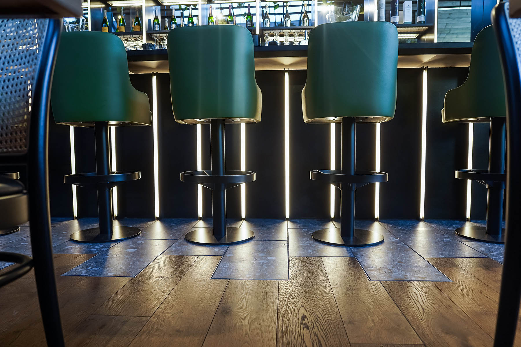 Dynamic bar area showcasing rich walnut tones and contrasting patterned tiles at Burleigh Court Hotel.