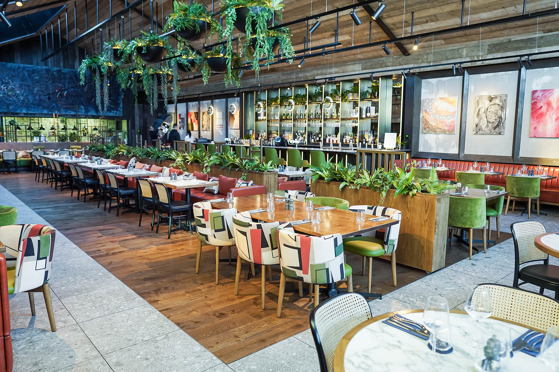 Seating area with natural wood tones, lush greenery, and bold patterned upholstery at Burleigh Court Hotel’s Fifty The Street.