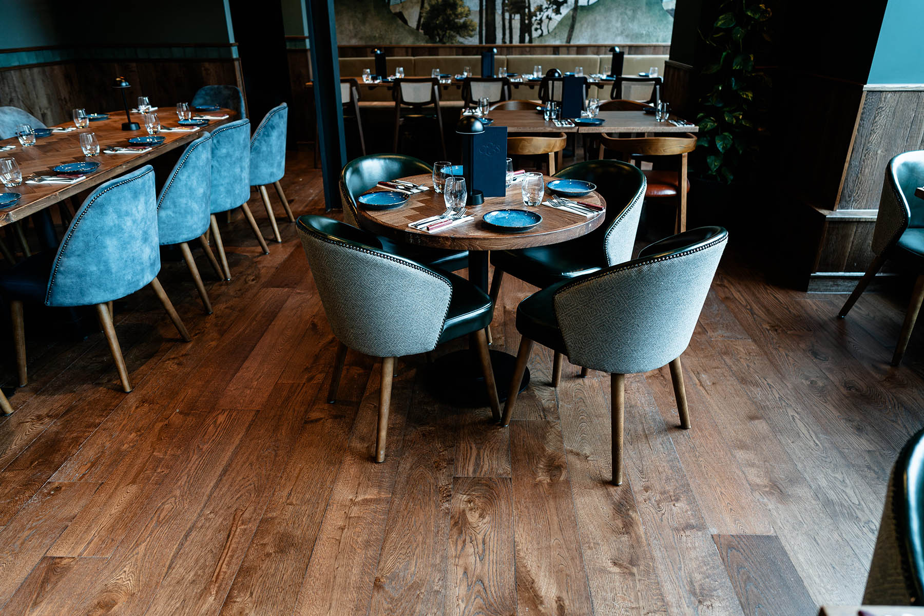 Modern restaurant interior with oak flooring and teal furnishings
