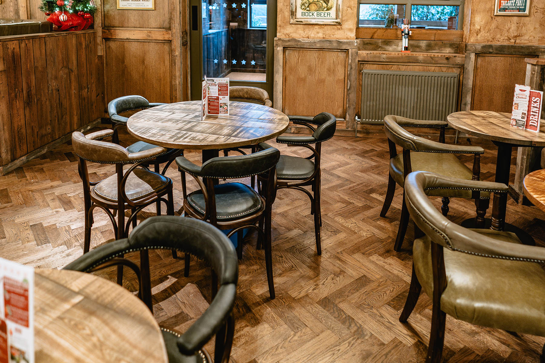 Warm, detailed herringbone wood flooring enhancing a cozy bar ambiance.
